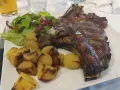 Succulenta costata di manzo alla griglia, servita con patate arrosto croccanti e un'insalata fresca. Un piatto da vero intenditore.