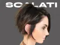 Modello con un audace taglio scalato medio corto, che incornicia il viso con ciocche texturizzate e un tocco di balayage.