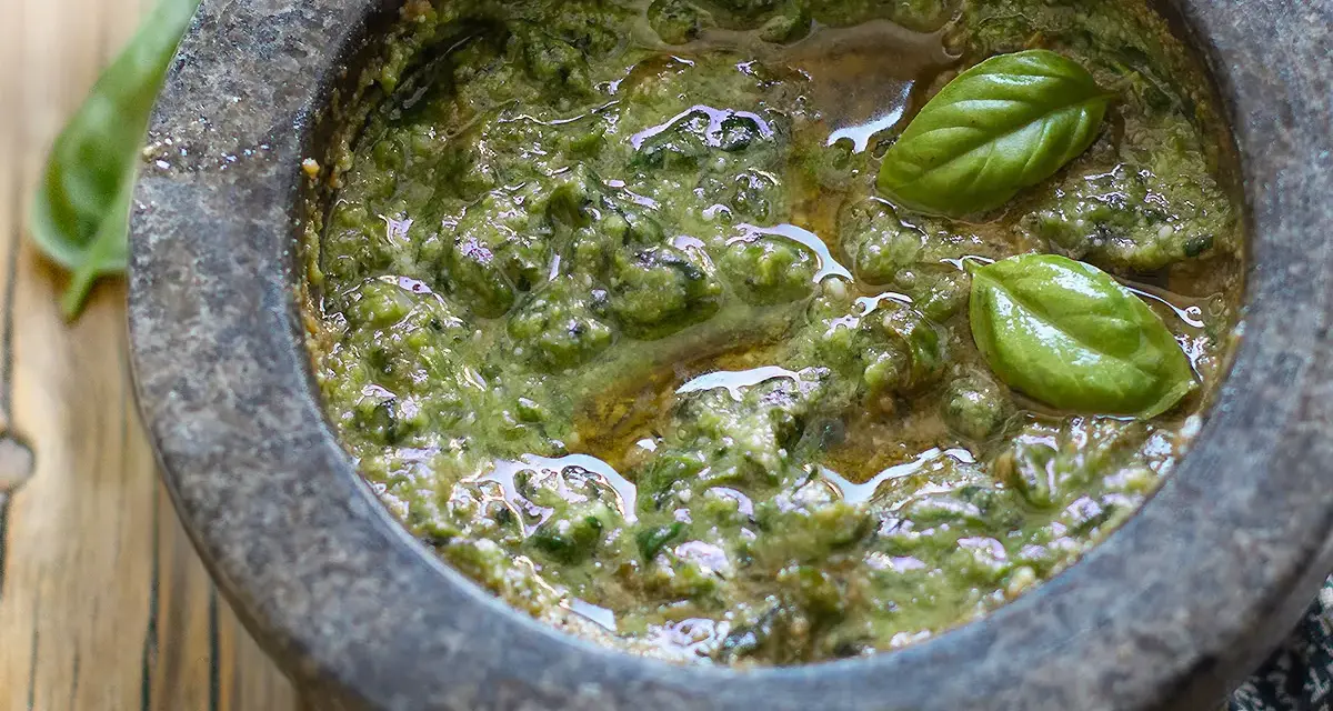 Pesto genovese originale appena preparato nel mortaio, con basilico fresco e olio d'oliva.