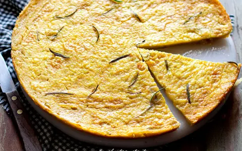 Farinata di ceci dorata e profumata al rosmarino, appena sfornata e tagliata a spicchi, pronta per essere gustata.