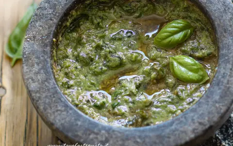 Pesto genovese originale appena preparato nel mortaio, con basilico fresco e olio d'oliva.