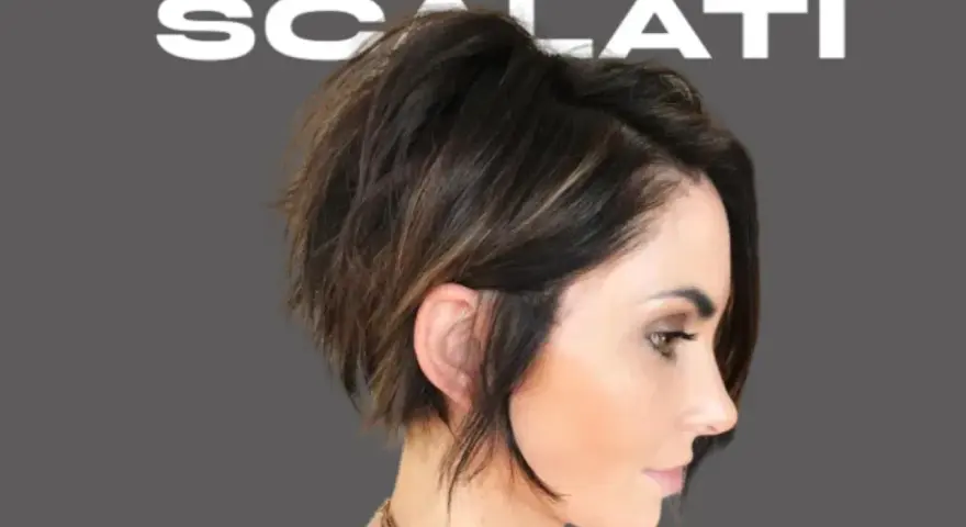 Modello con un audace taglio scalato medio corto, che incornicia il viso con ciocche texturizzate e un tocco di balayage.