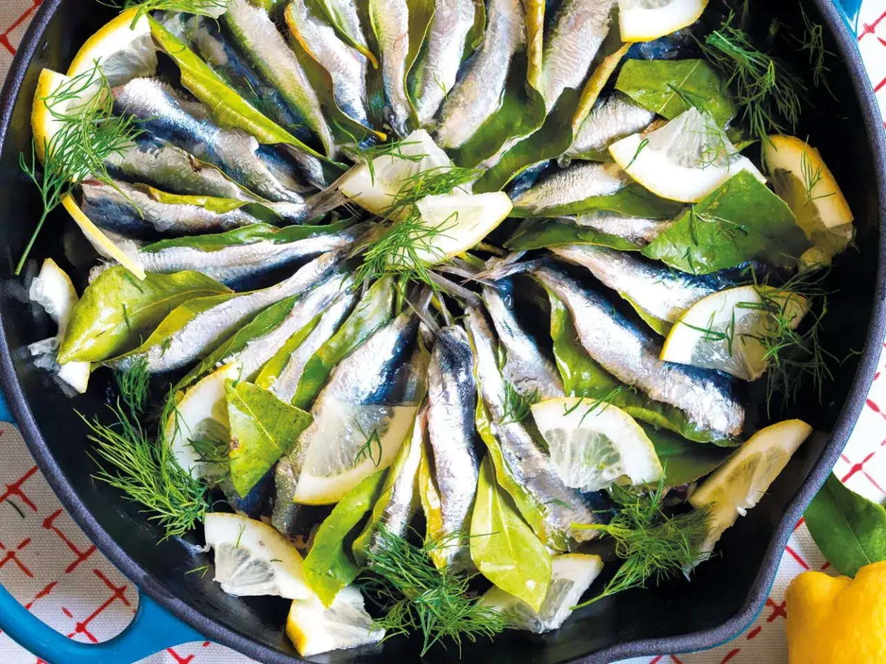 Sardine in padella con limone, alloro e finocchietto, pronte per essere cucinate.