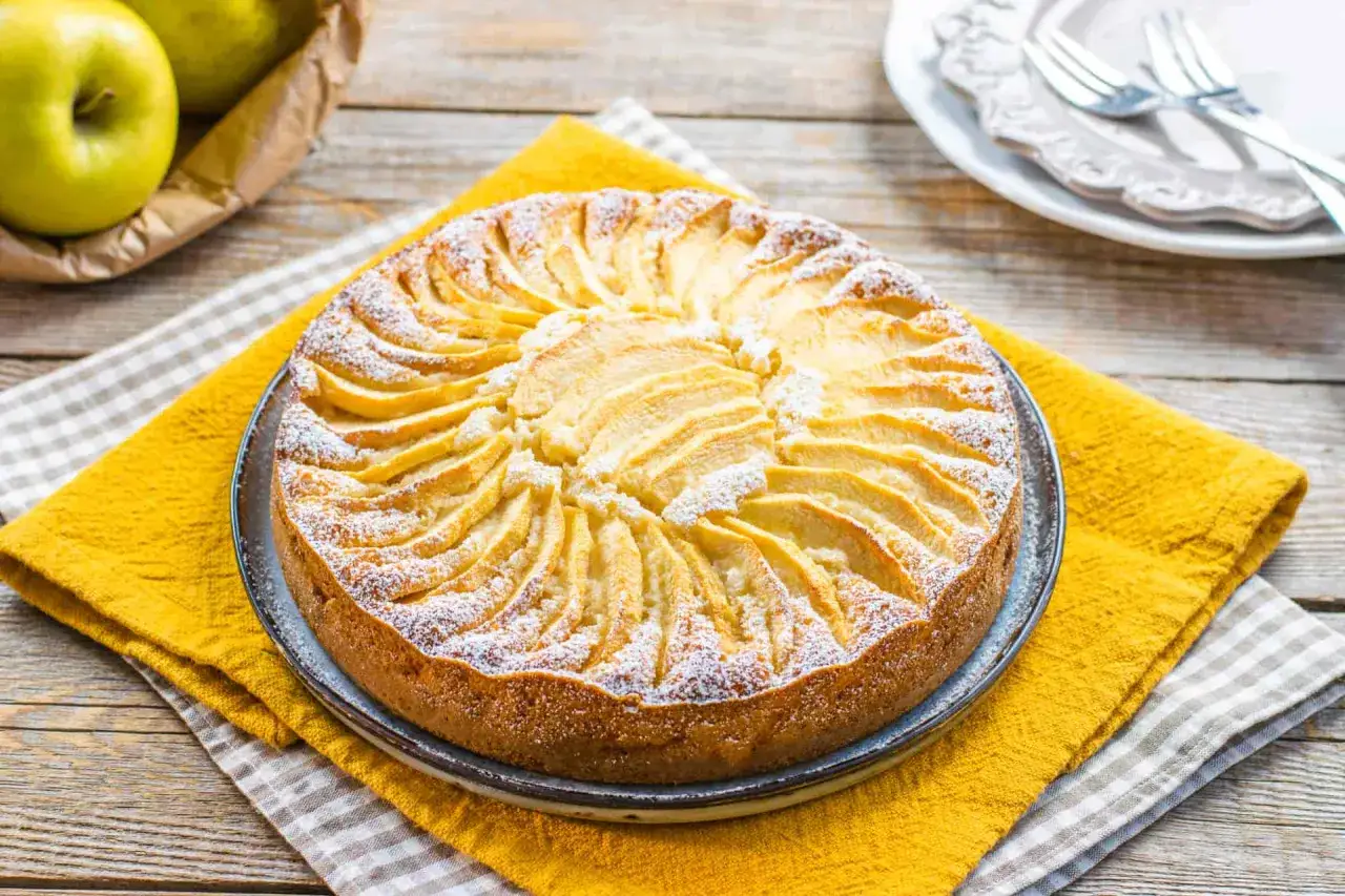 Torta di mele decorata con fettine disposte a raggiera, spolverata di zucchero a velo. Un'idea per dolci senza zucchero, gustosa e salutare.