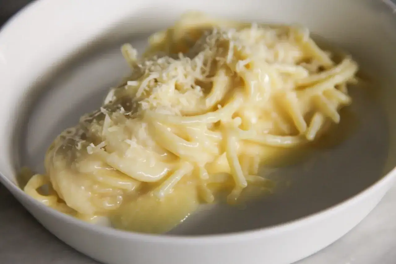 Un piatto di pasta burro e parmigiano, cremoso e invitante, con una spolverata di formaggio grattugiato.
