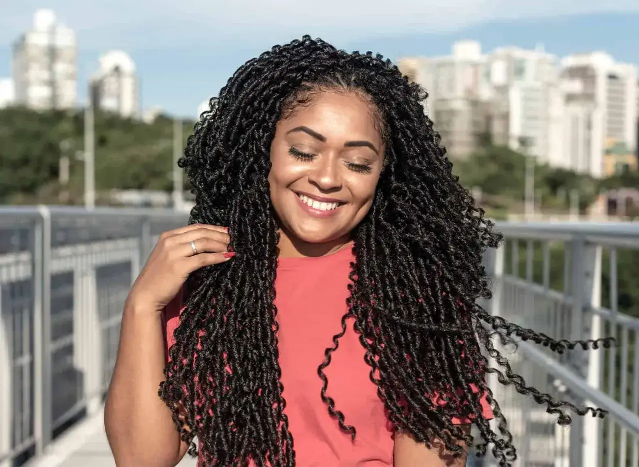 Donna sorridente con lunghi treccine africane che le incorniciano il viso.