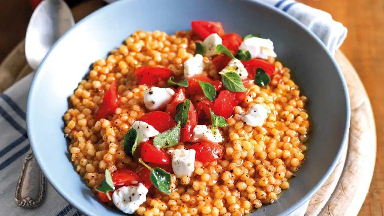 Fregola sarda con pomodorini, mozzarella e basilico. Un piatto colorato e gustoso, perfetto per le tue fregola ricette semplici.