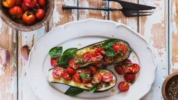 Melanzane ripiene vegetariane con pomodorini, basilico e semi di zucca, un piatto colorato e saporito.